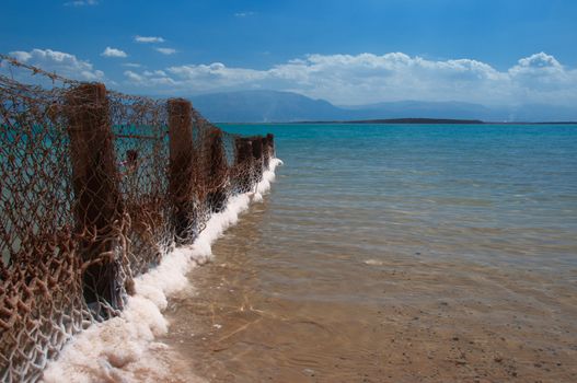 A fence separates the beach hotels covered Dead Sea salts