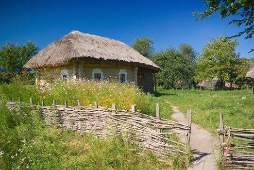 beautiful countryside with old fence and house, blue cloudy sky in background