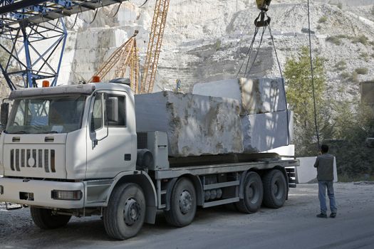 Marble quarry in the mountains near Carrara - Tuscany - Italy. A lorry is being loaded with big blocks of marble.