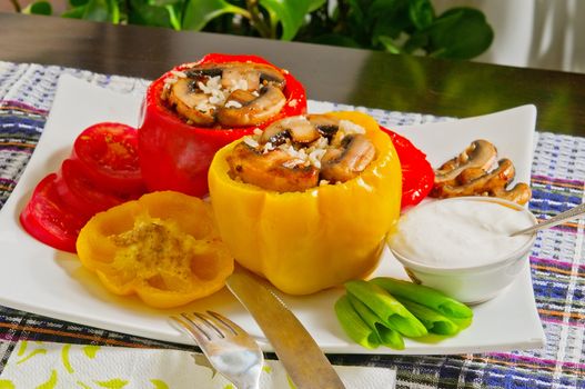 Bulgarian peppers stuffed with rice and mushrooms near a plate with sour cream