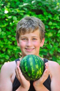 Boy holding watermelon while holding it with both hands