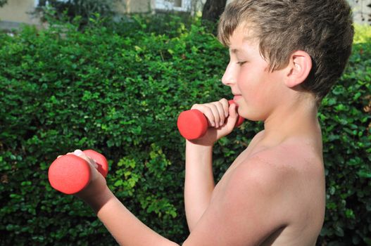 A boy plays sports in the yard of red dumbbell raises