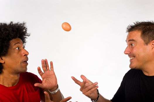 Two guys fooling around with an uncooked egg