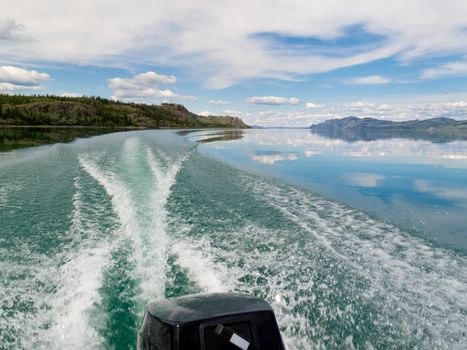 Wake of fast outboard motorboat on beautiful Lake Laberge, Yukon Territory, Canada.