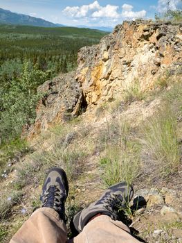 Tired hiker taking a rest overlooking rocky terrain and beautiful scenery in boreal forest of Yukon Territory, Canada.