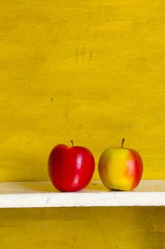 Apples on white shelve yellow wall background. Healthy ecologic fruit food.