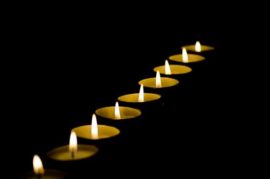 Row of candles in darkness with shallow depth of field and copy space