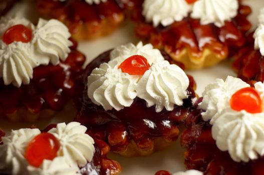 Small cupcakes with white cream and cherry on top. Shallow DOF.