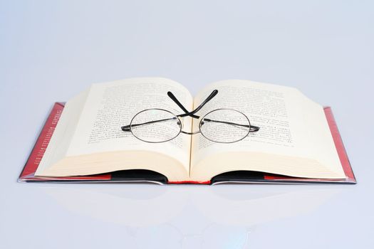 open book with a pair of eye glasses on top
