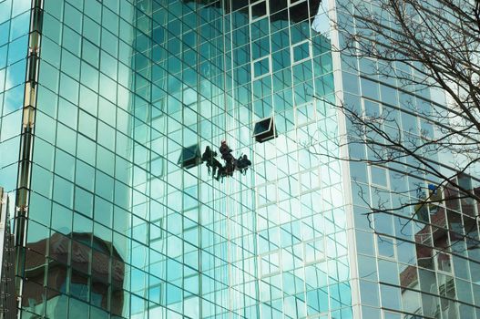 worker climbing at mirror wall of office building