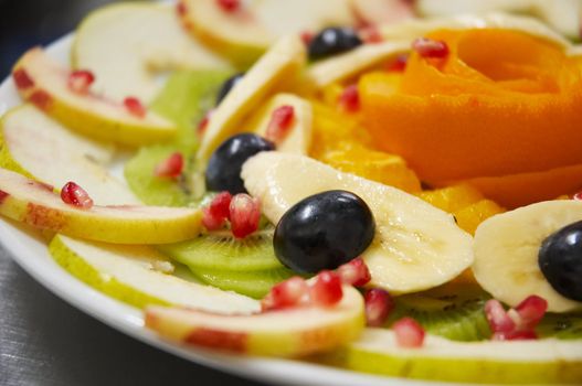 Perfectly designed fresh juicy fruit salad on plate.
Close-up series. Shallow DOF.