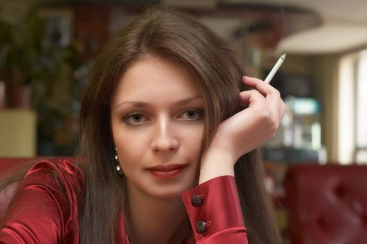 Sexy brunette in red with smoking cigarette