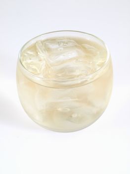 An alcoholic beverage over ice in a small clear glass, studio isolated on a white background.