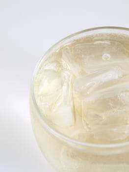 Close side framed view of an alcoholic beverage over ice in a small clear glass, studio isolated on a white background.