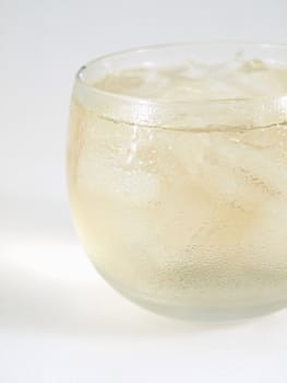 Close side view of an alcoholic beverage over ice in a small clear glass, studio isolated on a white background.