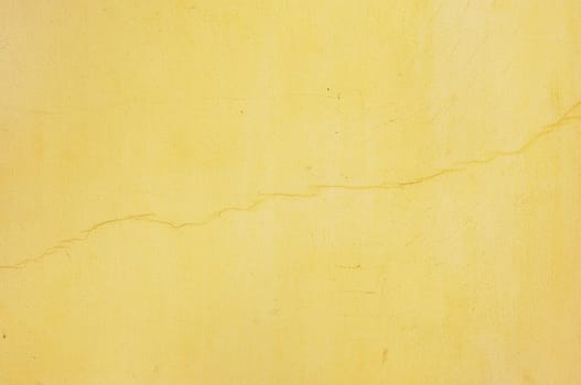 yellow unevenly painted stucco with thin diagonal crack