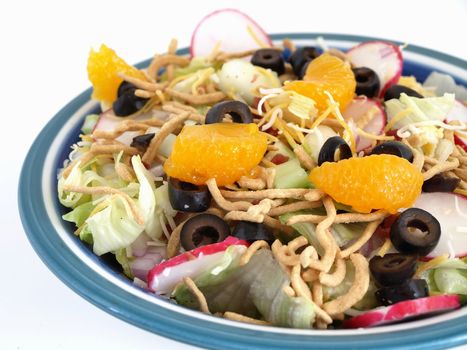 Crisp salad of lettuce, radishes, olives, mandarin oranges, cheese and Chinese noodles. Studio isolated over white.