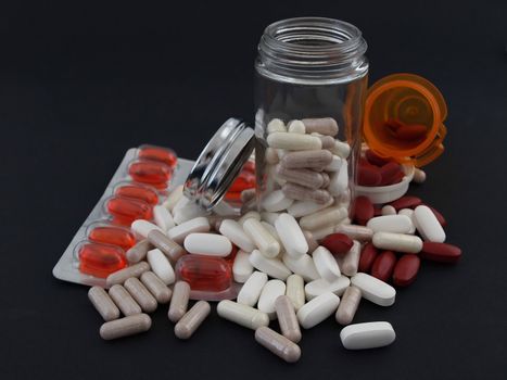 Various pills and pill bottles, studio isolated over a black background.