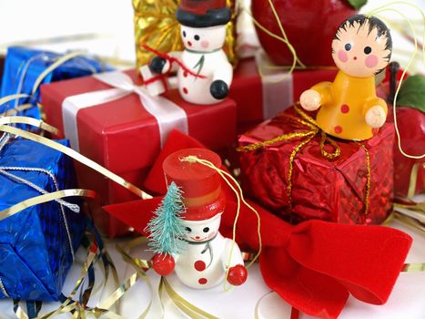 Cute colorful wooden Christmas tree ornaments, displayed with colorful wrapped presents. Over white.