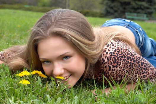 pretty girl smells dandelion on the green meadow