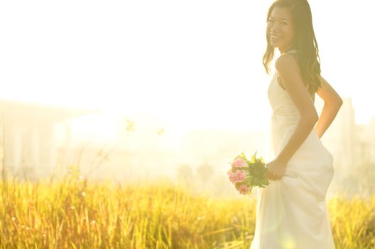 Asian bride at outdoor in a morning surrounding by golden sunlight