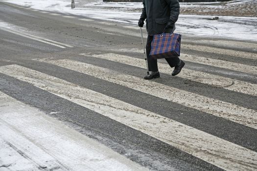 Disabled male senior in crosswalk at wintertime.