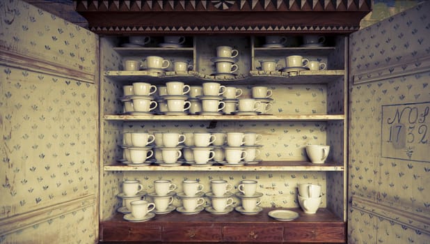 Beautiful antique Swedish cupboard from 1732 filled with cups. Cross processed to underline the mood.