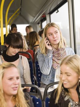 Young woman on the phone while going by the bus