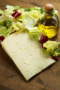 Asiago cheese with fresh salad on wooden table