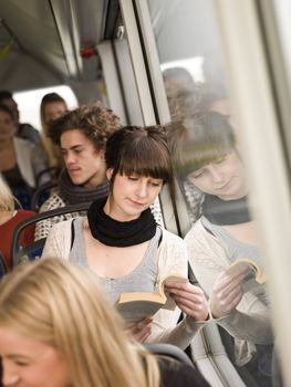 Young woman reading a book while going by the bus