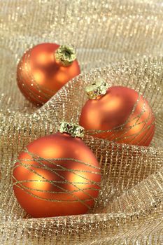 three Christmas balls on golden decorative fabric