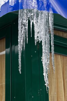 melting icicles and water drops from a metal building with trapulin roof