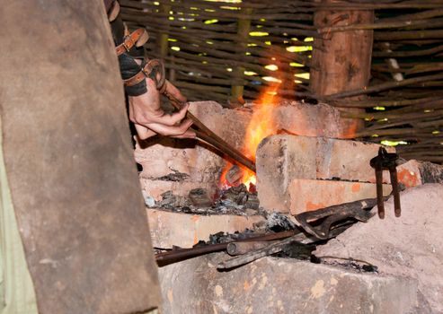 Blacksmith working a piece of metal in a medieval forge