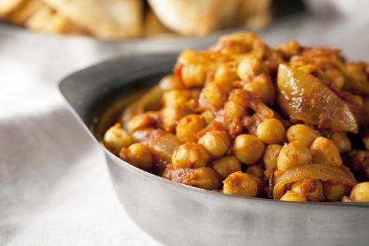 Fresh tomato and chickpea curry in metal bowl.