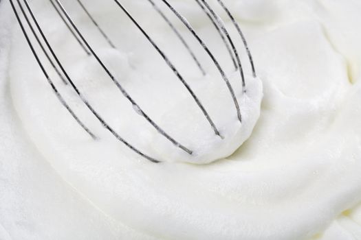 Closeup of whisk in beaten egg whites.