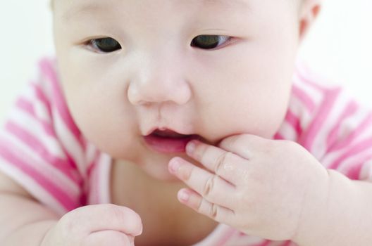 Curious Asian baby licking her fingers