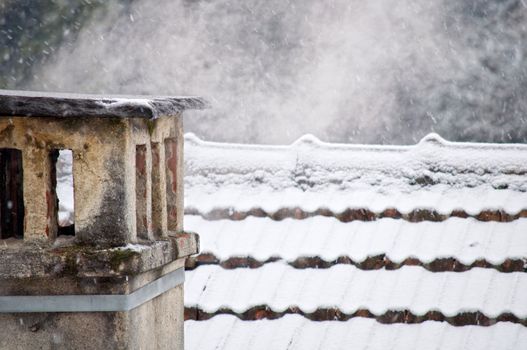 Chimney with smoke on snow covered roof