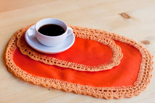 A coffee cup on two orange napkins on a wood table
