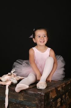 Cute little brunette girl trying on ballet pointe shoes
