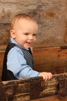 Baby boy playing inside an antique trunk