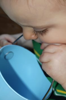 Baby boy looking into an empty blue bucket