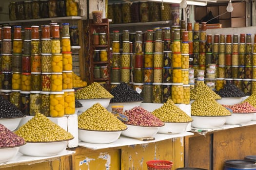 Market stall selling fresh olives and bottled food in the main souk of Marrakesh, Morocco.