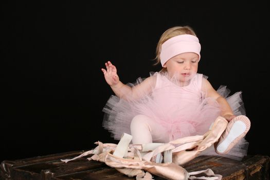 Blond toddler wearing a tutu holding Ballet shoes 