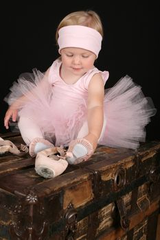 Blond toddler wearing a tutu holding Ballet shoes 