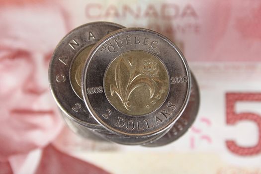 Stack of Canadian two dollar coins on top of af fifty dollar note