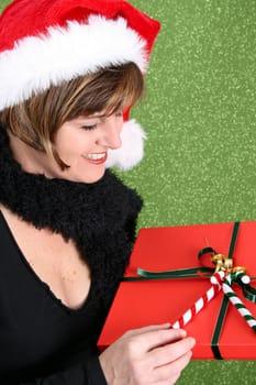 Beautiful brunette female wearing a christmas hat, holding gift