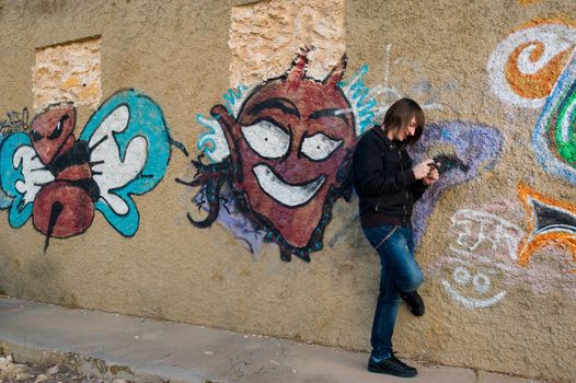 Teen playing with a console in a grunge urban setting