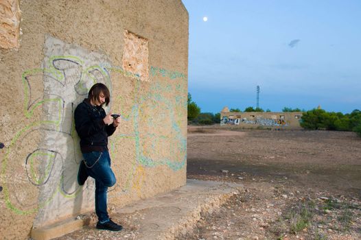 Teen playing with a console in a grunge setting