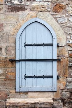 old wooden door with padlock on the wall made from stone