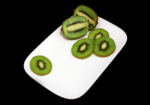 sliced fresh juicy kiwi on the plate on black